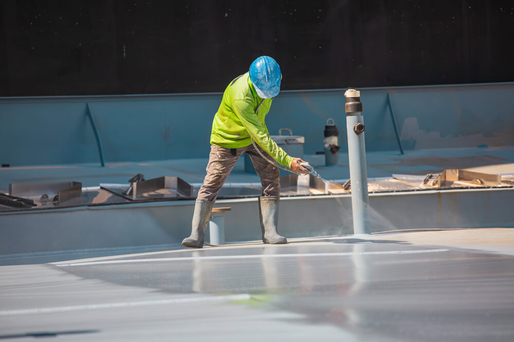 Top view male worker holding an industrial spray gun used for roof plate tank surface on steel industrial painting